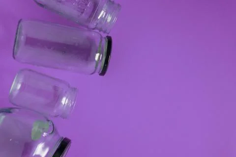 Isolated glass jars, flat on violet purple background, room copy space right Stock Photos