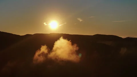 Isolated glowing mist cloud floating below sunrise sun over terrain Stock Footage 336280443