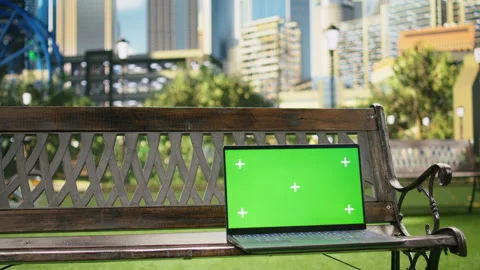Isolated green screen on laptop placed on wooden bench in city park Stock Footage 343502103