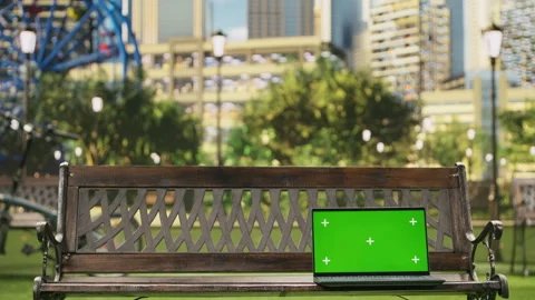 Isolated green screen on laptop placed on wooden bench in city park Stock Footage 343507605