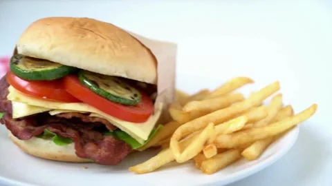 Isolated hamburger rotates on table wood background, and french fries rotating Video stock 336579435