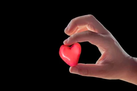Isolated Hand holding a red candy shape heart on a black background. Stock Photos