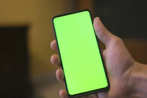 Isolated human hand holding a green screen smartphone,hi tech addiction concept Stock Photos