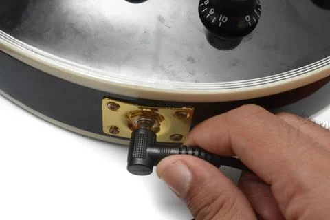 Isolated image of a man hand is plug in the guitar cable into the guitar jack so Stock Photos