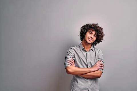 Isolated image of smiling eastern young man with crossed hands Stock Photos