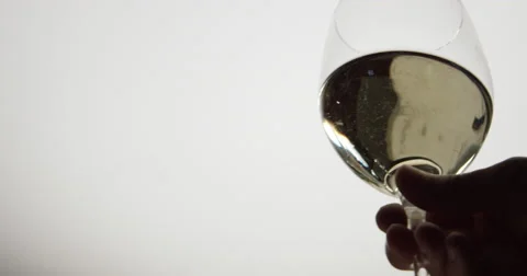 Isolated low angle of a caucasian hand lifting a glass of white white. Stock Footage 64043156
