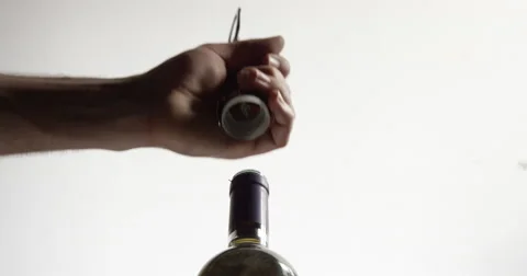 Isolated low angle profile shot of Caucasian hands uncorking bottle of wine. Stock Footage 64038421