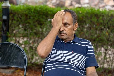 Isolated old man having eye strain at outdoor park at evening from flat angle Fotos de archivo