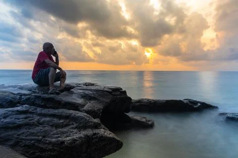 Isolated old man talking on mobile long exposure blur with sunrise sky and .. 库存照片
