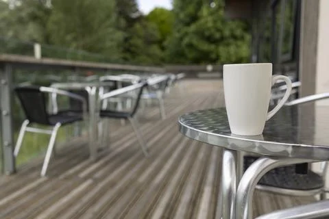Isolated plain white coffee cup on a aluminium cafe table selective focus Stock Photos