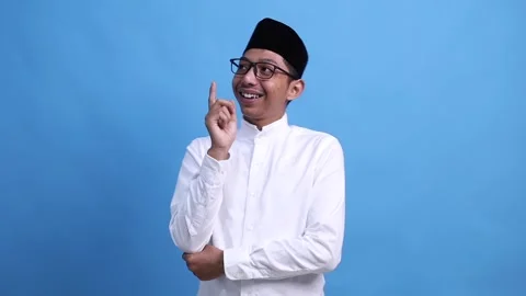 Isolated portrait on blue background of young pensive asian muslim man, holding Stock Footage 301756516