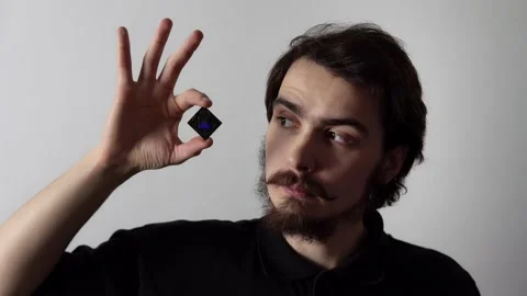 Isolated portrait of man holding microchip by fingers and showing it looking at Stock Footage 159680036