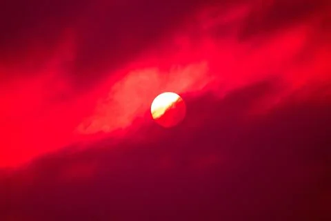 Isolated red background and sun behind the clouds Stock Photos