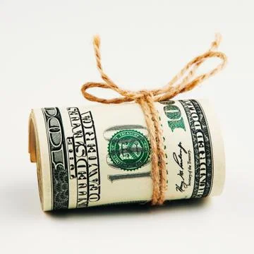 Isolated roll of dollars. A large roll of hundred-dollar bills lies on a whit Stock Photos