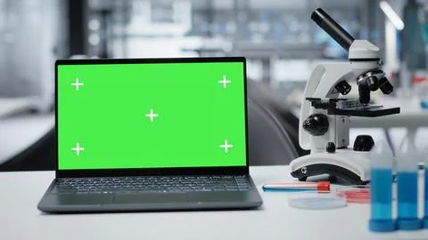 Isolated screen laptop on lab workbench next to microscope and liquid samples 스톡 사진