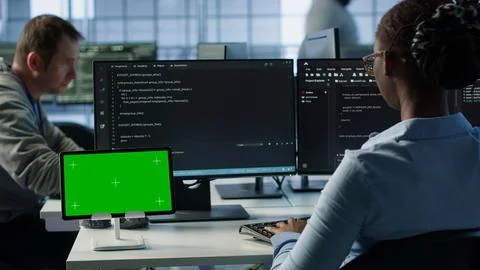 Isolated screen tablet in front of IT support workers coding on computers Stock Photos