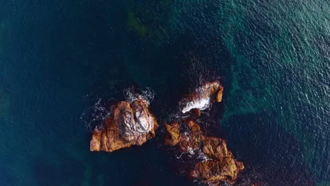 Isolated sea rocks emerging from deep teal water, top down view. Three weathered Stock Footage 336782795