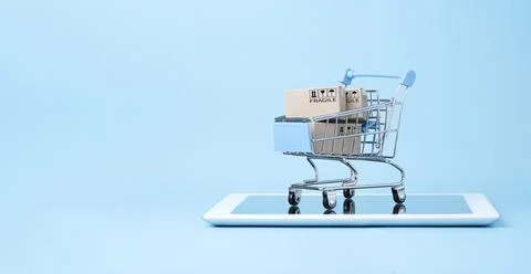 Isolated of Shipping paper boxes inside blue shopping cart trolley on tablet Stock Photos