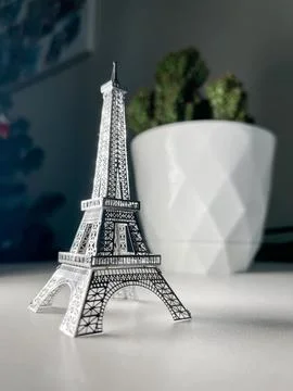An isolated silver Eiffel Tower model on a white background with a blurred ba Stock Photos