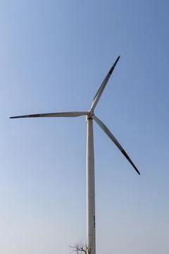 Isolated single wind turbine generating renewable energy against clear blue s Foto stock