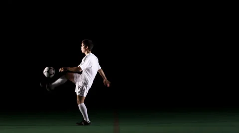 Isolated soccer player on black does tricks with the ball Stock Footage 33867886