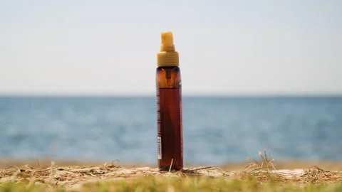 Isolated sunscreen bottle, sea in background, static medium shot. Stock Footage 132304369