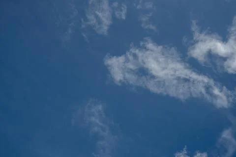 Isolated thin white cloud patches against a deep blue sky Stock Photos