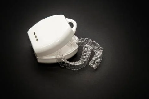 Isolated transparent teeth prosthesis with its box over black for design Photos