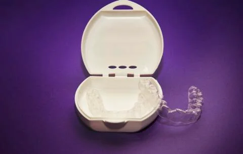 Isolated transparent teeth prosthesis with its box over purple for design 库存照片