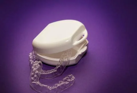 Isolated transparent teeth prosthesis with its box over purple for design Foto stock