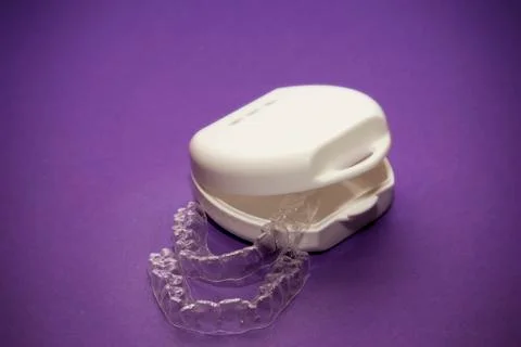 Isolated transparent teeth prosthesis with its box over purple for design Foto stock