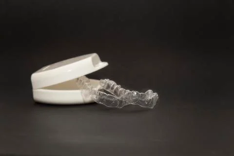 Isolated transparent teeth prosthesis with its box over black for design Foto stock