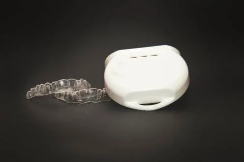 Isolated transparent teeth prosthesis with its box over black for design Photos