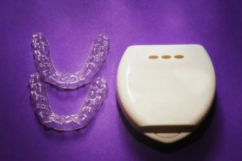 Isolated transparent teeth prosthesis with its box over purple for design Foto stock