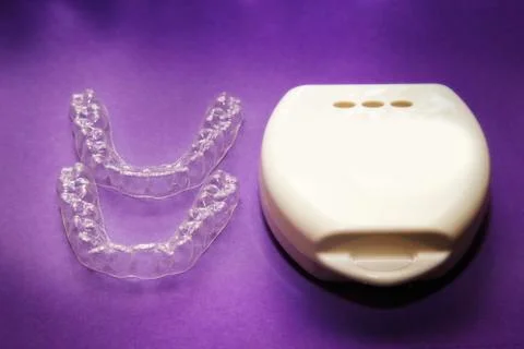 Isolated transparent teeth prosthesis with its box over purple for design Фото