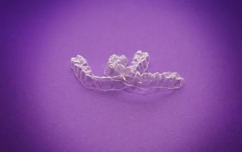Isolated transparent teeth prosthesis over purple for design Foto stock