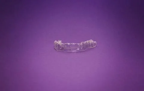Isolated transparent teeth prosthesis over purple for design Foto stock