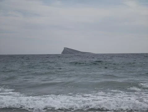 Isolated triangular islet amidst stormy waters, secluded triangular rock Stock Photos