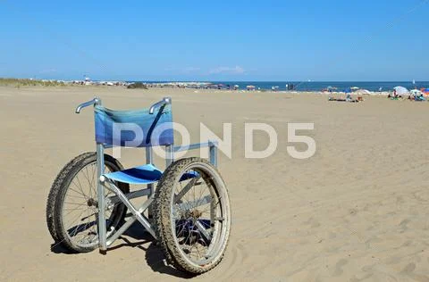Isolated wheelchairs for people with mobility problems on the sea beach in su Stock Photos