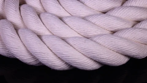 Isolated white cable in flat roll on black backdrop close up, rotating to right Stock Footage 84113533
