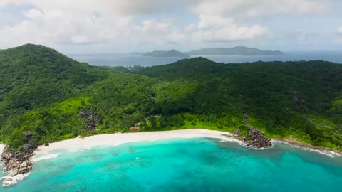 Isolated white sandy beach surrounded by dense green forest. La Digue Stock Footage 314535611