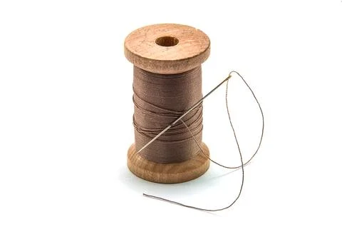 Isolated wooden spool of brown thread with a needle Stock Photos