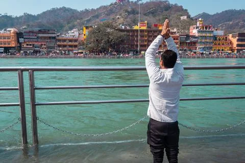 Isolated young man prying the holy ganges river at river bank from flat angle Foto stock