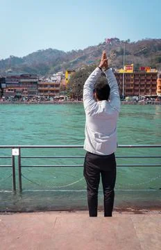 Isolated young man prying the holy ganges river at river bank from flat angle 스톡 사진