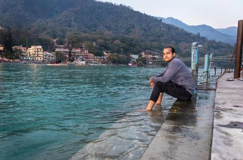 Isolated young man sitting at ganges river bank from flat angle 스톡 사진