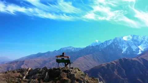 In isolation. One in whole world. Man sitting on bench at top of a mountain. Stock Footage 144189713