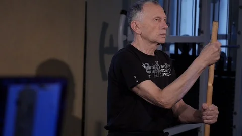Isometric exercise with a stick.an elderly man holds a stick vertically in front Stock Footage 115850356
