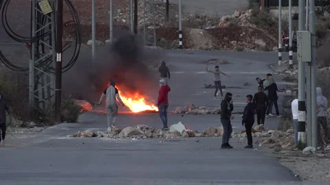 Israel Palestine conflict, young men throw stones, burn tires in Ramallah Stock Footage