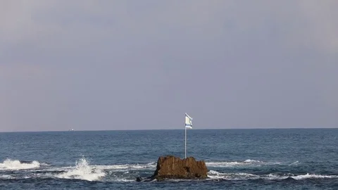 Israeli flag is flying over a small island in the sea near the shore. Stock Footage 80975307