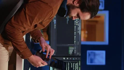 IT admin holding table, using it as reference while coding on computer Stock Footage 265108000